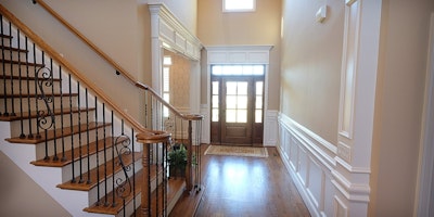 Entry way with vaulted ceilings, white decorative wood trim, staircase and hardwood floors